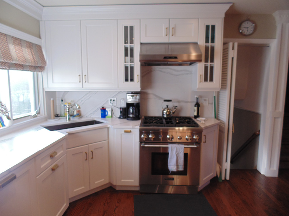 Example of a mid-sized transitional u-shaped medium tone wood floor and brown floor eat-in kitchen design with an undermount sink, recessed-panel cabinets, white cabinets, quartz countertops, white backsplash, stone slab backsplash, stainless steel appliances, no island and white countertops