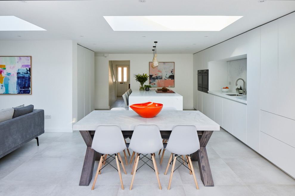 Design ideas for a large contemporary single-wall open plan kitchen in Kent with an undermount sink, flat-panel cabinets, white cabinets, quartz benchtops, white splashback, engineered quartz splashback, stainless steel appliances, ceramic floors, with island and white benchtop.