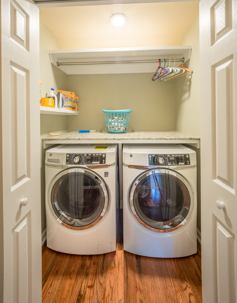 Small traditional single-wall laundry cupboard in Jacksonville with quartz benchtops, beige walls, medium hardwood floors, a side-by-side washer and dryer, brown floor and multi-coloured benchtop.