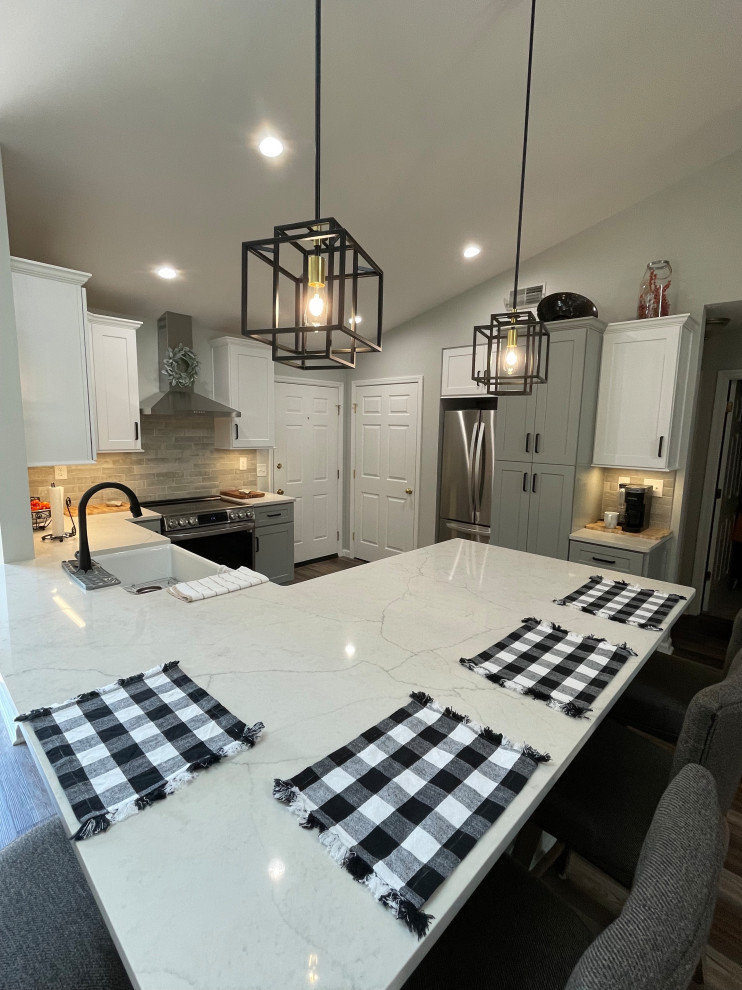 Inspiration for a mid-sized transitional u-shaped vinyl floor and brown floor eat-in kitchen remodel with a farmhouse sink, shaker cabinets, white cabinets, quartz countertops, gray backsplash, subway tile backsplash, stainless steel appliances, no island and white countertops