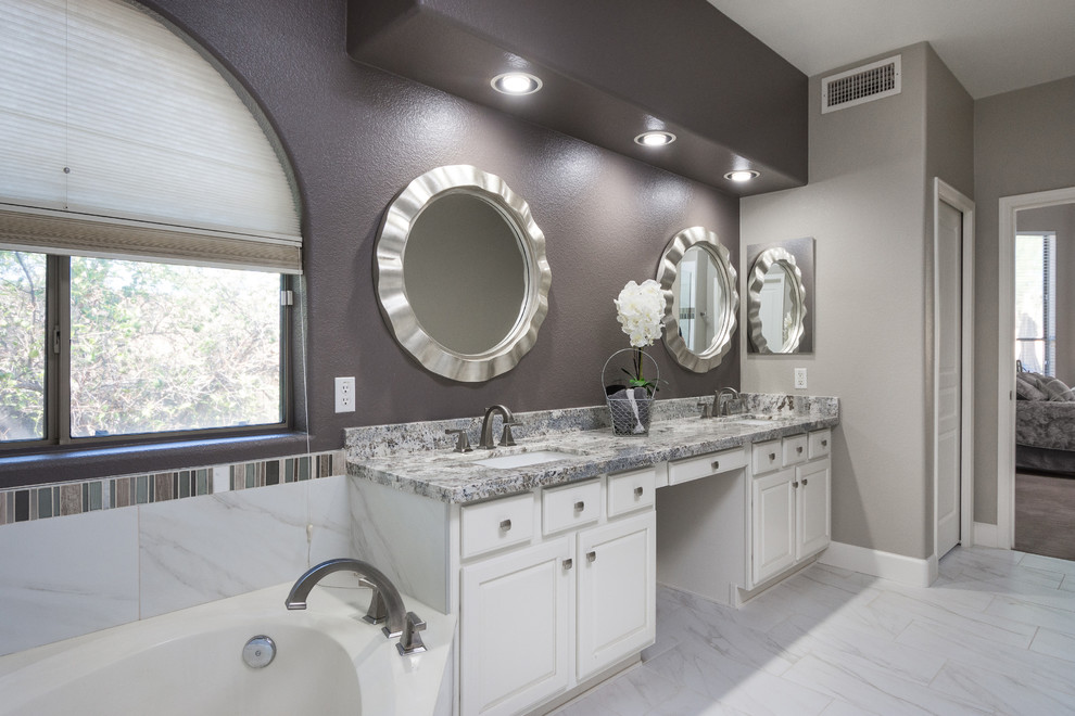 This is an example of a mid-sized transitional master bathroom in Phoenix with raised-panel cabinets, white cabinets, a corner tub, black and white tile, glass tile, grey walls, porcelain floors, an undermount sink and granite benchtops.