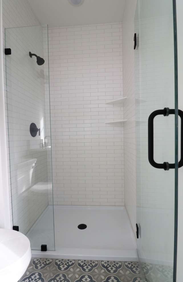 Inspiration för ett medelhavsstil vit vitt badrum med dusch, med möbel-liknande, en dusch i en alkov, en toalettstol med hel cisternkåpa, vit kakel, tunnelbanekakel, vita väggar, cementgolv, ett undermonterad handfat, marmorbänkskiva och dusch med gångjärnsdörr