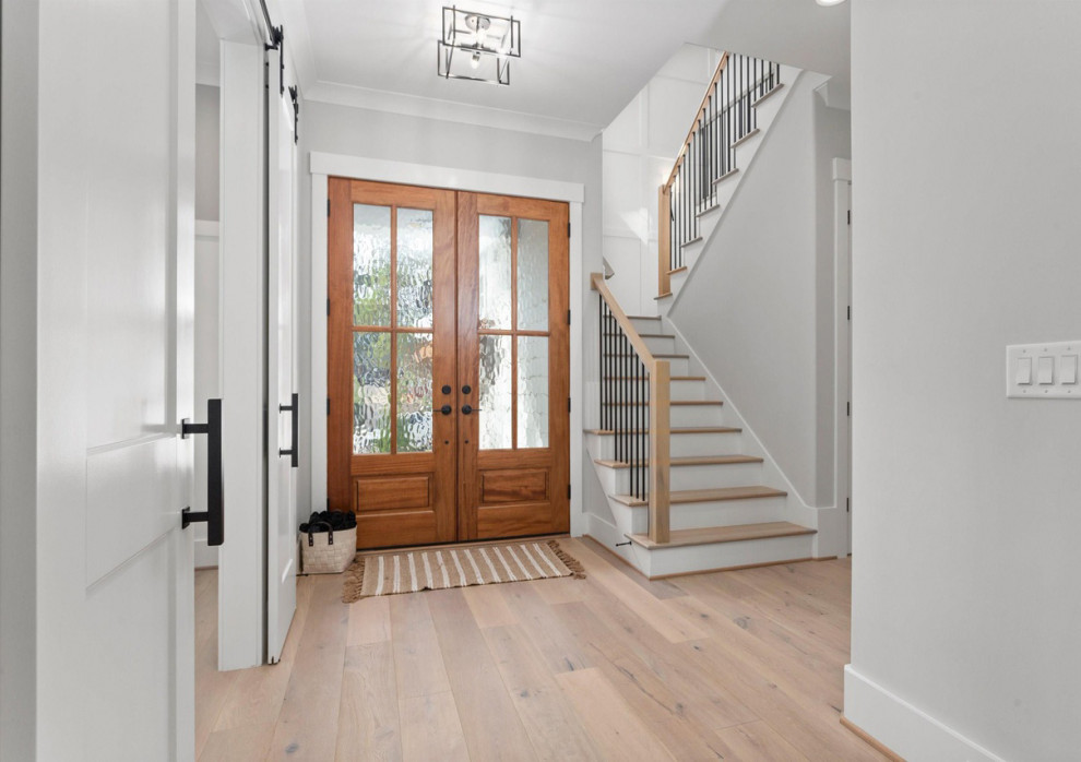 Ejemplo de puerta principal abovedada minimalista grande con paredes blancas, suelo de madera clara, puerta doble, puerta de madera en tonos medios, suelo multicolor y machihembrado