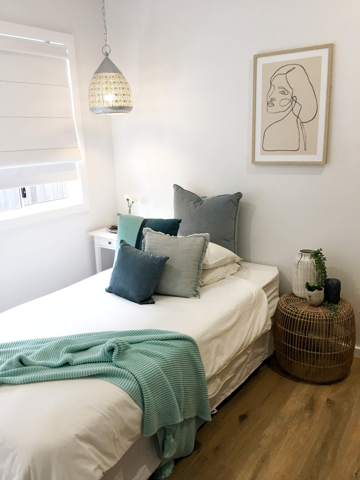 Photo of a small beach style master bedroom in Sydney with white walls and laminate floors.
