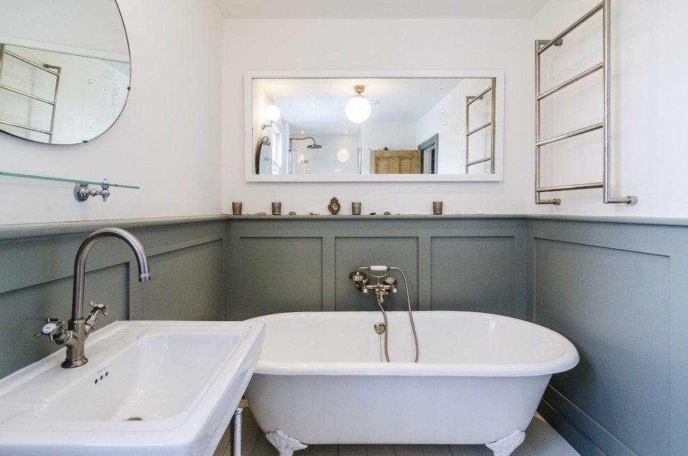 Design ideas for a mid-sized traditional kids bathroom in London with a console sink, recessed-panel cabinets, grey cabinets, wood benchtops, a claw-foot tub, an alcove shower, a two-piece toilet, white tile, porcelain tile, white walls and painted wood floors.