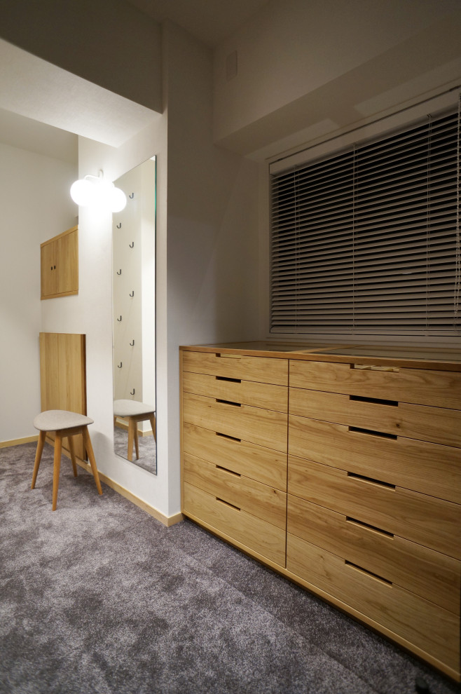Inspiration for a scandinavian gender-neutral walk-in wardrobe in Tokyo with light wood cabinets, carpet, grey floor and wallpaper.