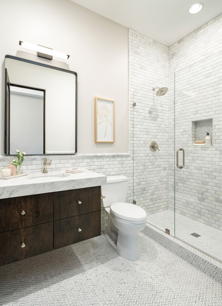 Пример оригинального дизайна: ванная комната среднего размера в стиле неоклассика (современная классика) с плоскими фасадами, темными деревянными фасадами, душем в нише, унитазом-моноблоком, белой плиткой, мраморной плиткой, серыми стенами, полом из керамогранита, врезной раковиной, мраморной столешницей, серым полом, душем с распашными дверями, белой столешницей, тумбой под одну раковину и подвесной тумбой