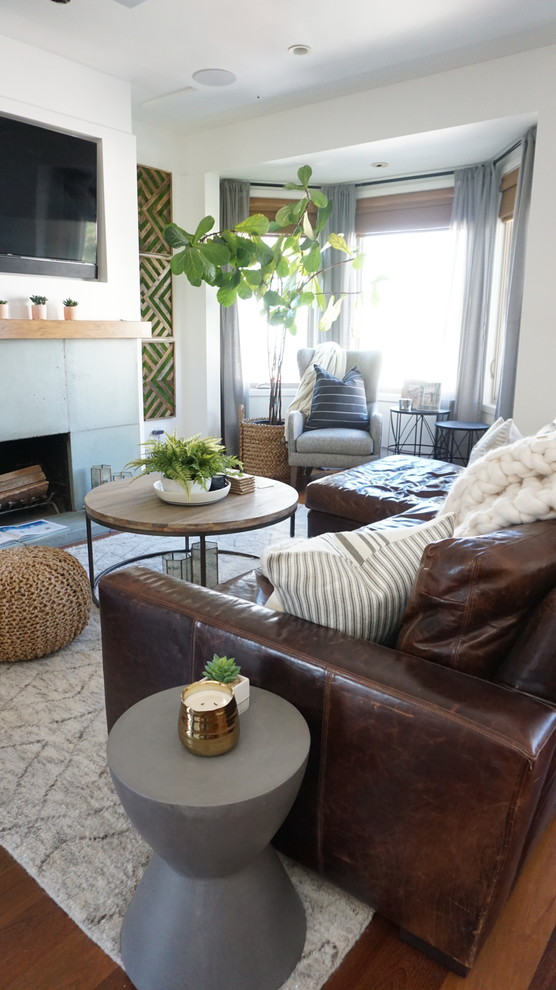 This is an example of a mid-sized eclectic open concept family room in San Francisco with white walls, dark hardwood floors, a standard fireplace, a concrete fireplace surround, a wall-mounted tv and brown floor.