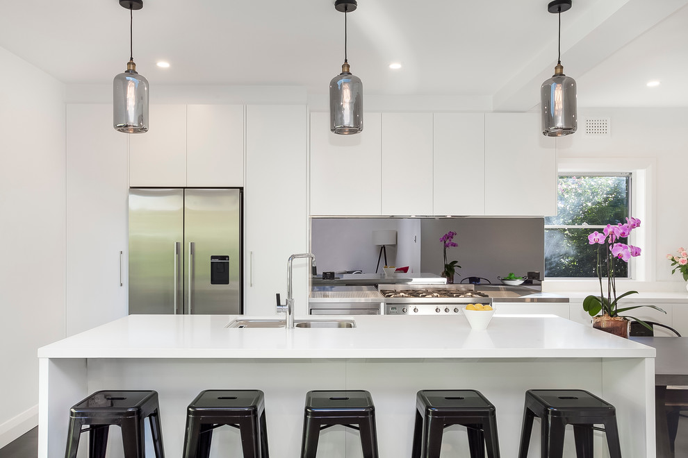 This is an example of a mid-sized contemporary galley eat-in kitchen in Sydney with a double-bowl sink, flat-panel cabinets, white cabinets, laminate benchtops, black splashback, mirror splashback, stainless steel appliances, dark hardwood floors and with island.