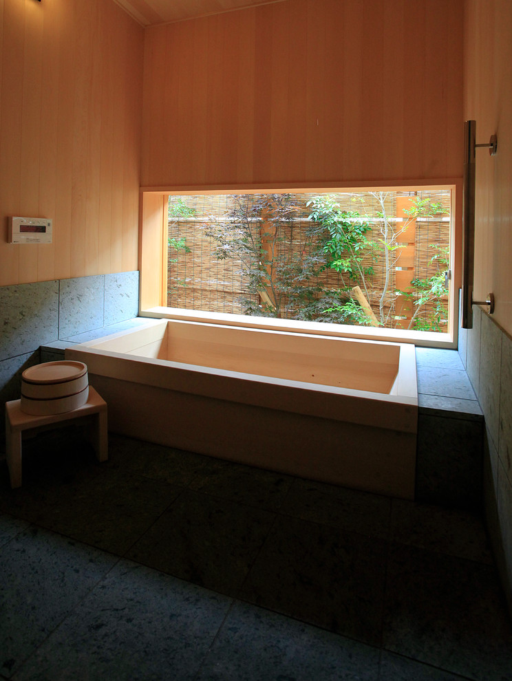 This is an example of an asian master bathroom in Other with a japanese tub, grey walls and wood walls.