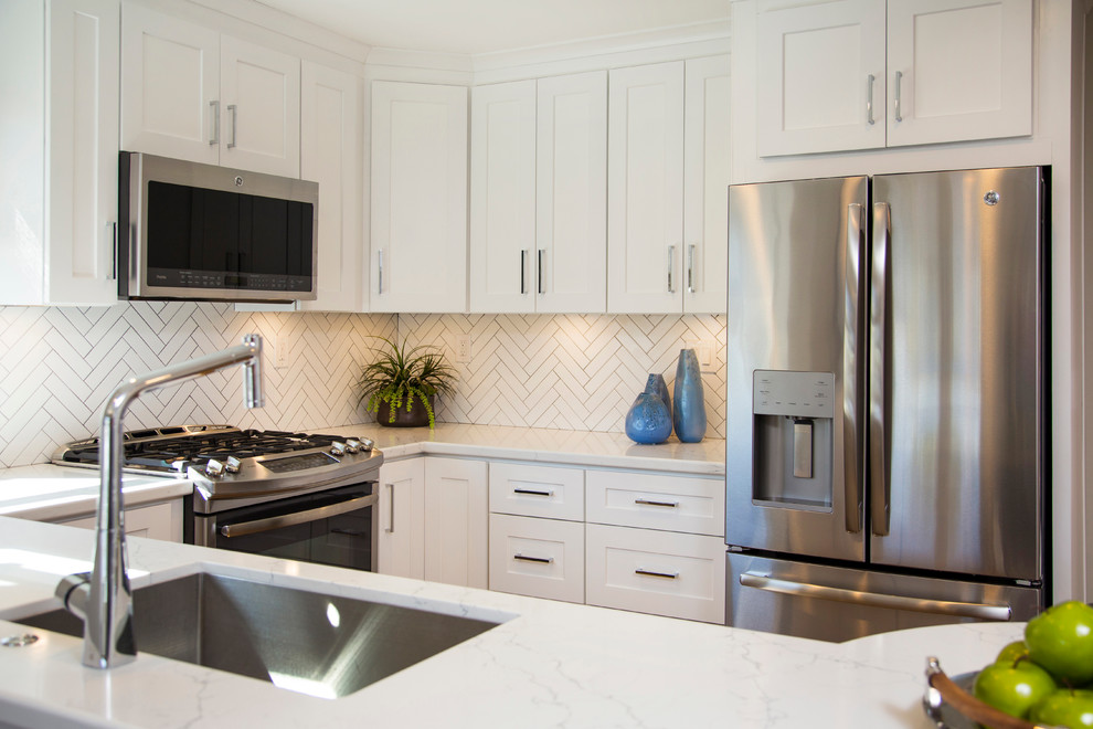 Example of a small transitional u-shaped medium tone wood floor open concept kitchen design in San Diego with an undermount sink, shaker cabinets, white cabinets, quartz countertops, white backsplash, ceramic backsplash, stainless steel appliances and a peninsula