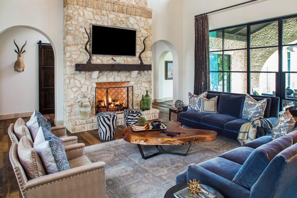 Mediterranean open concept family room in Austin with white walls, medium hardwood floors, a standard fireplace, a stone fireplace surround and a wall-mounted tv.