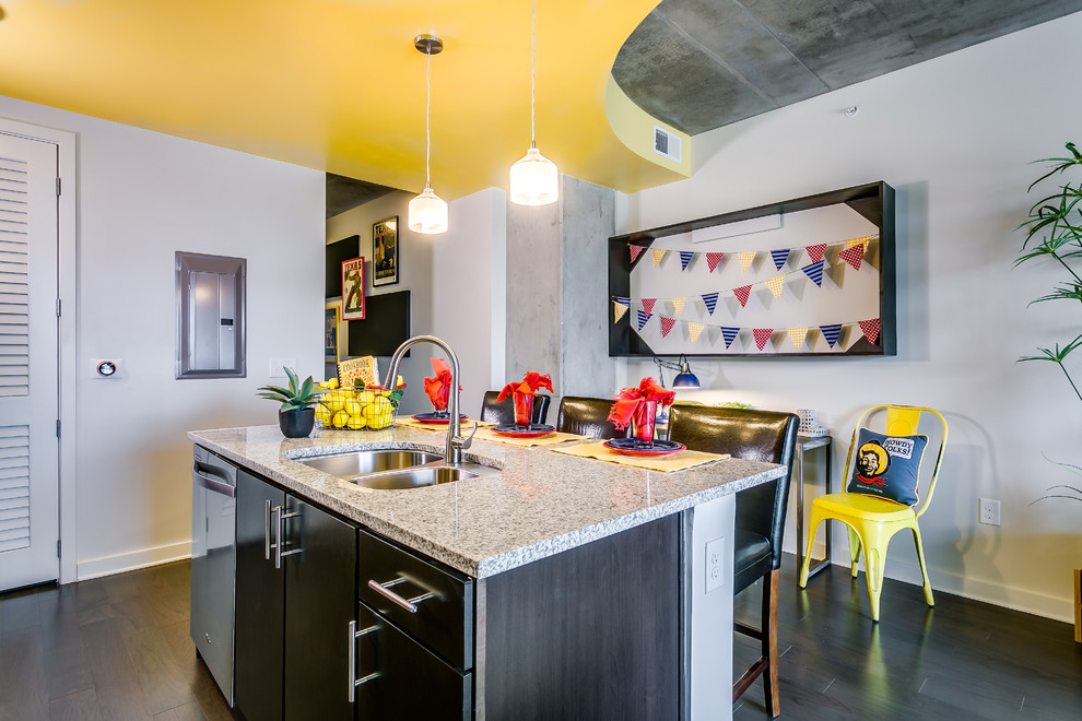 Example of a small transitional l-shaped medium tone wood floor and brown floor open concept kitchen design in Dallas with a double-bowl sink, flat-panel cabinets, dark wood cabinets, granite countertops, white backsplash, porcelain backsplash, stainless steel appliances and an island