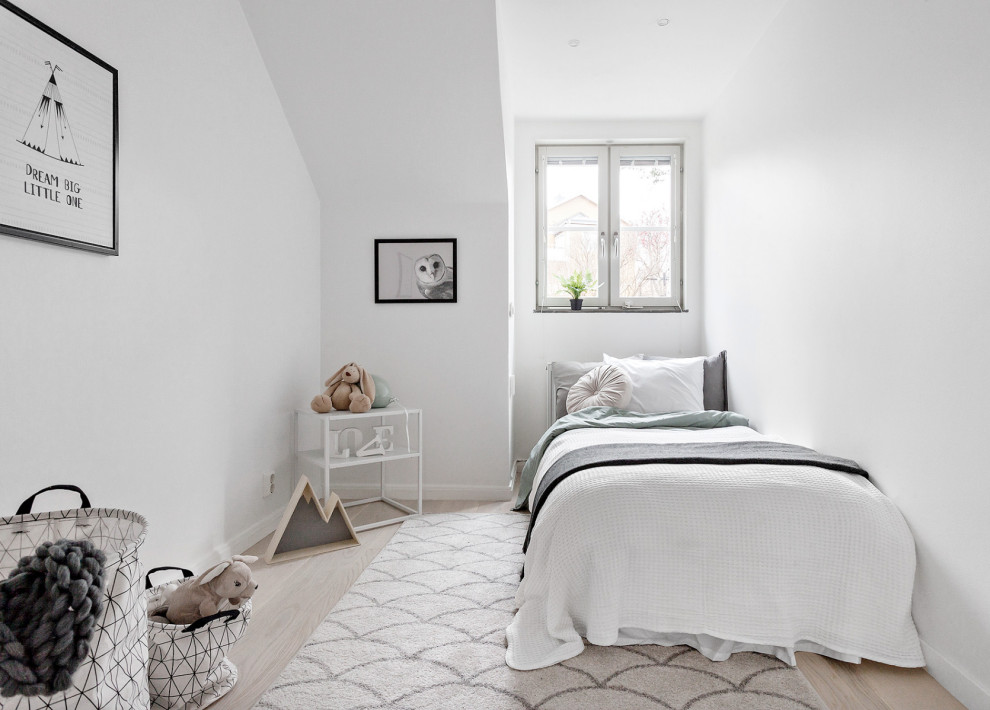 This is an example of a mid-sized scandinavian gender-neutral kids' bedroom for kids 4-10 years old in Stockholm with white walls, light hardwood floors and beige floor.