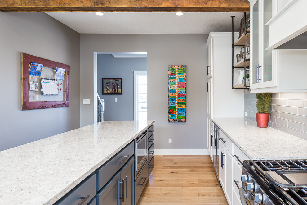Large transitional l-shaped eat-in kitchen photo with white cabinets, quartzite countertops, gray backsplash, glass tile backsplash, stainless steel appliances and an island