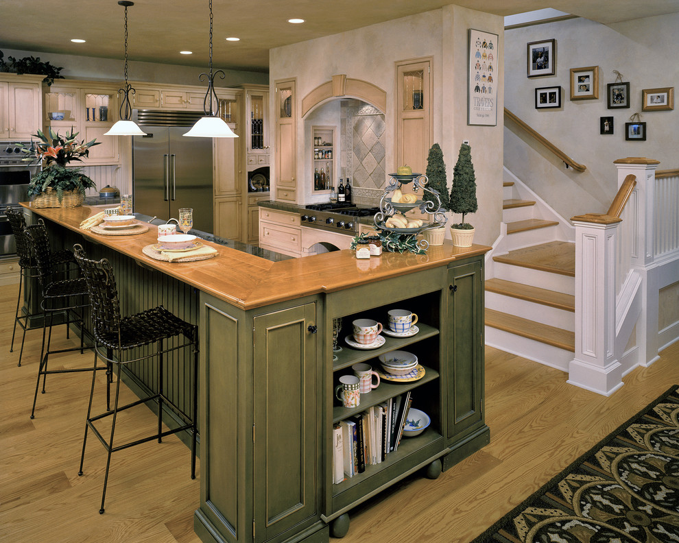This is an example of a country kitchen in New York with an undermount sink, beaded inset cabinets, green cabinets, wood benchtops, stone tile splashback and stainless steel appliances.