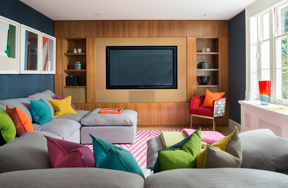 Photo of a mid-sized contemporary home theatre in London with blue walls, light hardwood floors, a built-in media wall and beige floor.