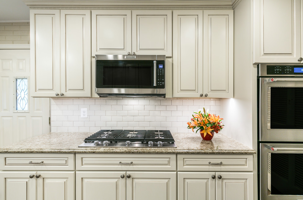 Design ideas for a mid-sized traditional galley eat-in kitchen in DC Metro with an undermount sink, raised-panel cabinets, white cabinets, quartz benchtops, white splashback, subway tile splashback, stainless steel appliances, dark hardwood floors, with island and brown floor.