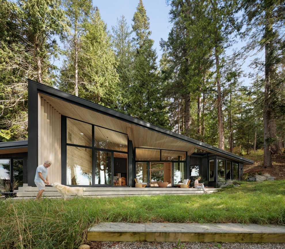 Idées déco pour une façade de maison noire montagne en bois de taille moyenne et de plain-pied avec un toit en appentis, un toit en métal et un toit noir.