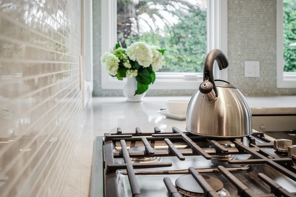 Eat-in kitchen - large transitional u-shaped limestone floor eat-in kitchen idea with an undermount sink, shaker cabinets, white cabinets, marble countertops, metallic backsplash, mosaic tile backsplash, stainless steel appliances and an island