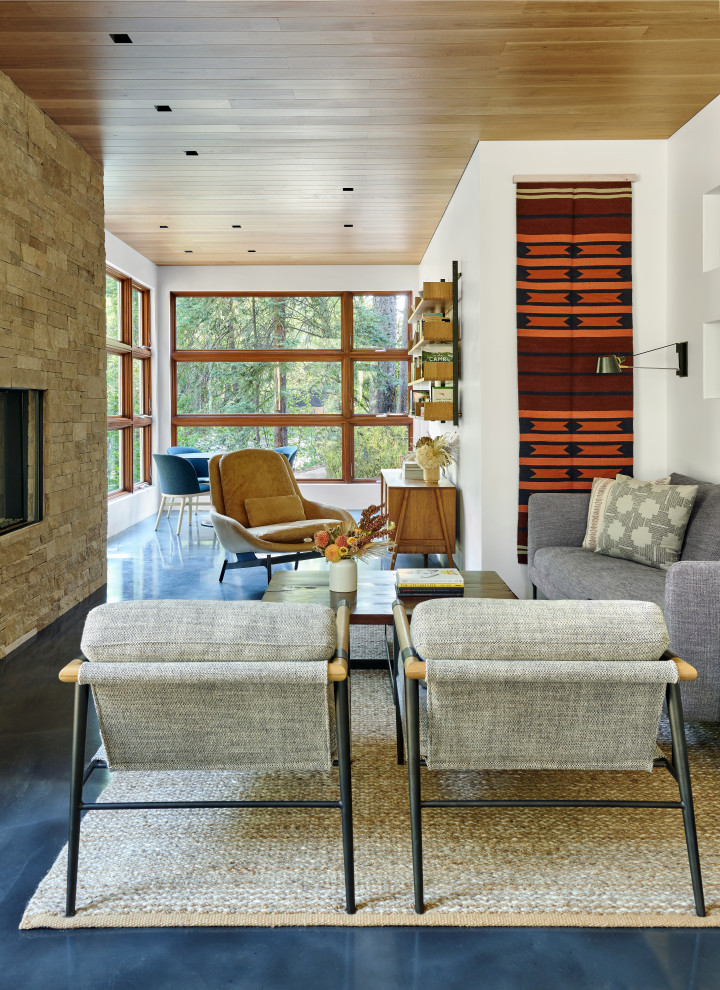 Стильный дизайн: открытая гостиная комната в современном стиле с белыми стенами, бетонным полом, стандартным камином, фасадом камина из каменной кладки, синим полом и деревянным потолком - последний тренд