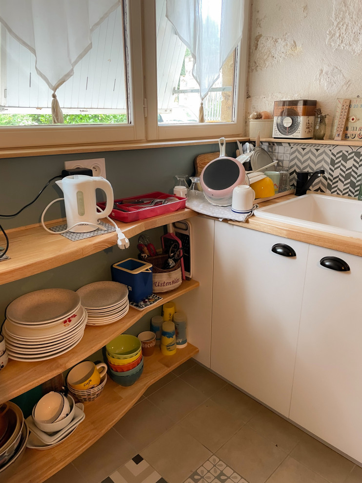 Foto på ett litet 60 tals kök, med en undermonterad diskho, luckor med profilerade fronter, vita skåp, träbänkskiva, flerfärgad stänkskydd, stänkskydd i keramik, vita vitvaror, klinkergolv i keramik, en halv köksö och beiget golv
