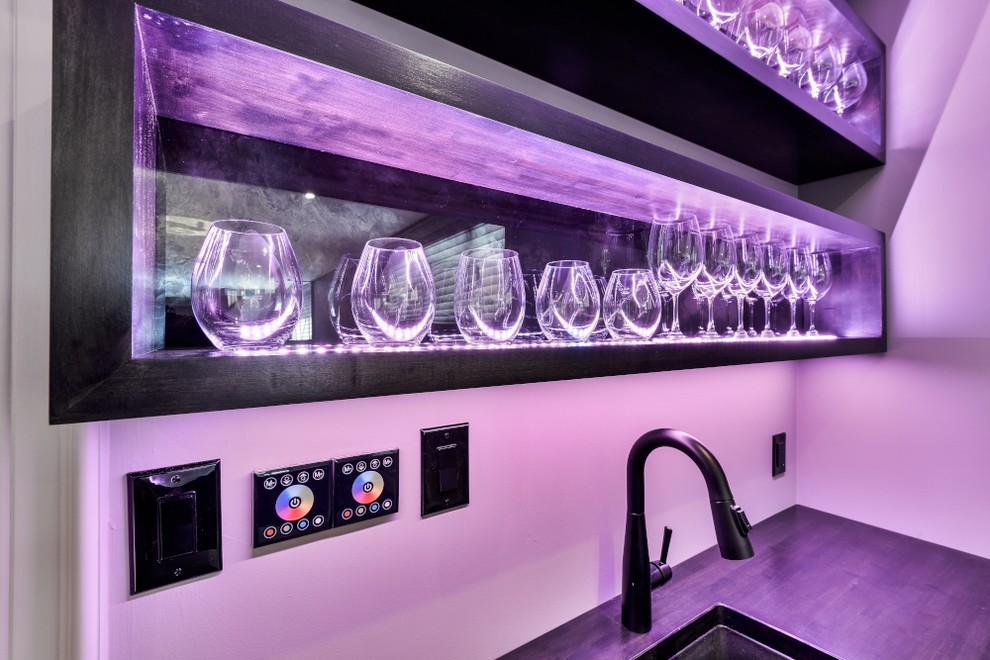 This is an example of a large modern l-shaped wet bar in Toronto with flat-panel cabinets, black cabinets and wood benchtops.