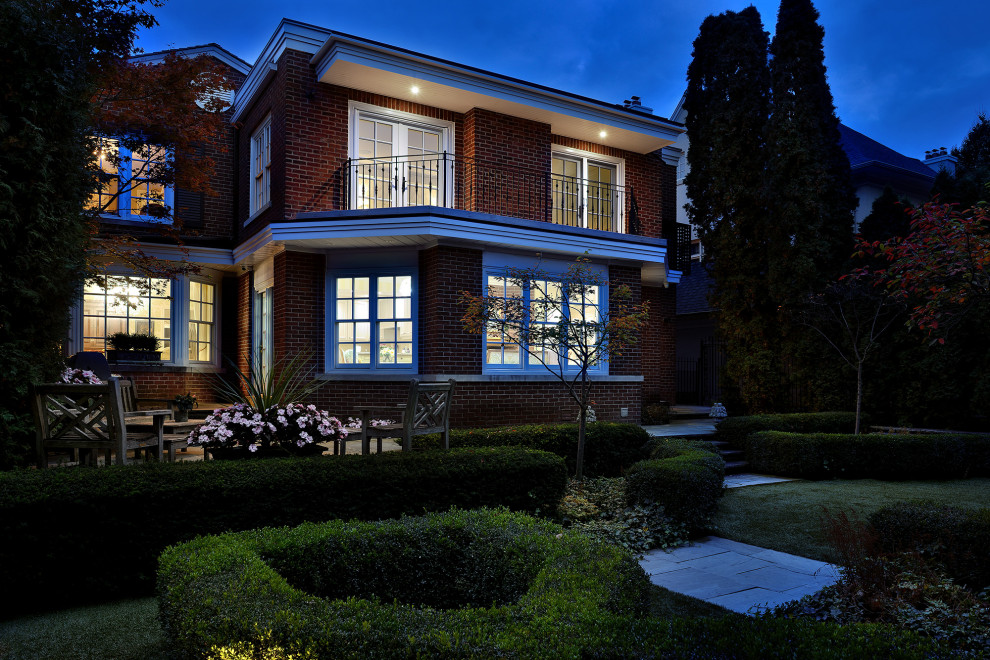 This is an example of a mid-sized traditional two-storey brick red house exterior in Toronto with a gable roof, a shingle roof and a brown roof.