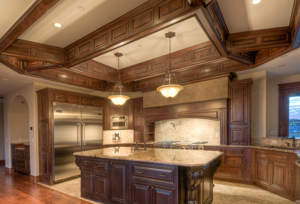 Large mountain style u-shaped travertine floor eat-in kitchen photo in Denver with an undermount sink, raised-panel cabinets, medium tone wood cabinets, granite countertops, beige backsplash, stainless steel appliances, beige walls and an island
