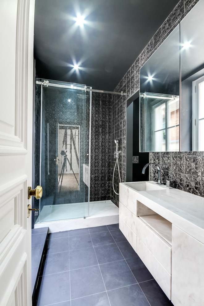 This is an example of a mid-sized contemporary 3/4 bathroom in Paris with an integrated sink, an undermount sink, flat-panel cabinets, white cabinets, an alcove shower, black tile, black walls and marble benchtops.