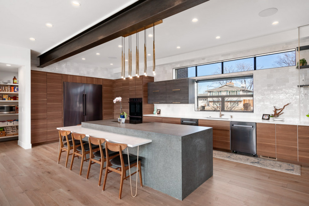 This is an example of a modern wet bar in Denver with an undermount sink, flat-panel cabinets, dark wood cabinets, concrete benchtops, white splashback, ceramic splashback, light hardwood floors and grey benchtop.