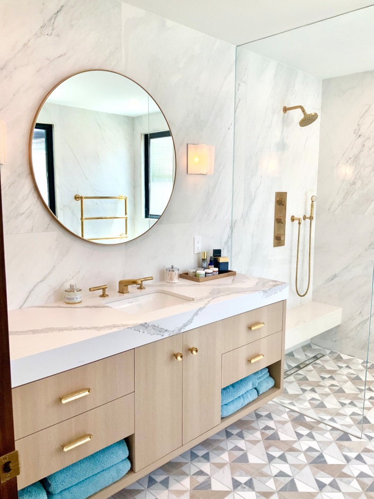 This is an example of a large traditional ensuite bathroom in Los Angeles with flat-panel cabinets, light wood cabinets, a freestanding bath, a walk-in shower, a bidet, white tiles, porcelain tiles, white walls, engineered stone worktops, beige floors, an open shower, white worktops, a single sink, a floating vanity unit, marble flooring and a submerged sink.