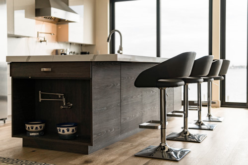 Modern kitchen island with built-in pet feeding nook and pull-out faucet above dog bowls