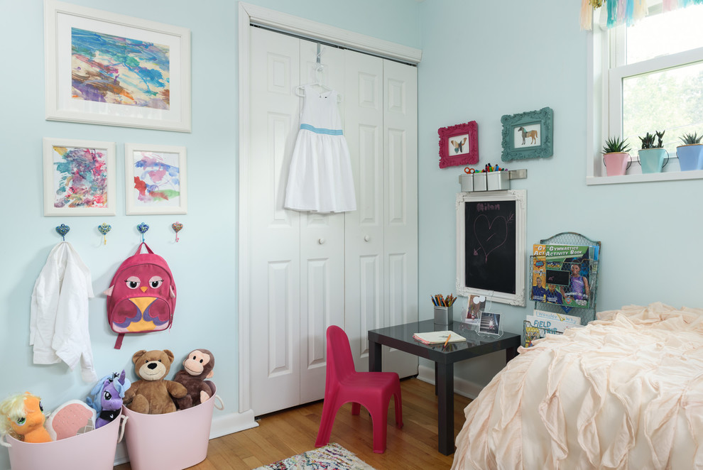 This is an example of a small traditional kids' bedroom for kids 4-10 years old and girls in DC Metro with blue walls and light hardwood floors.