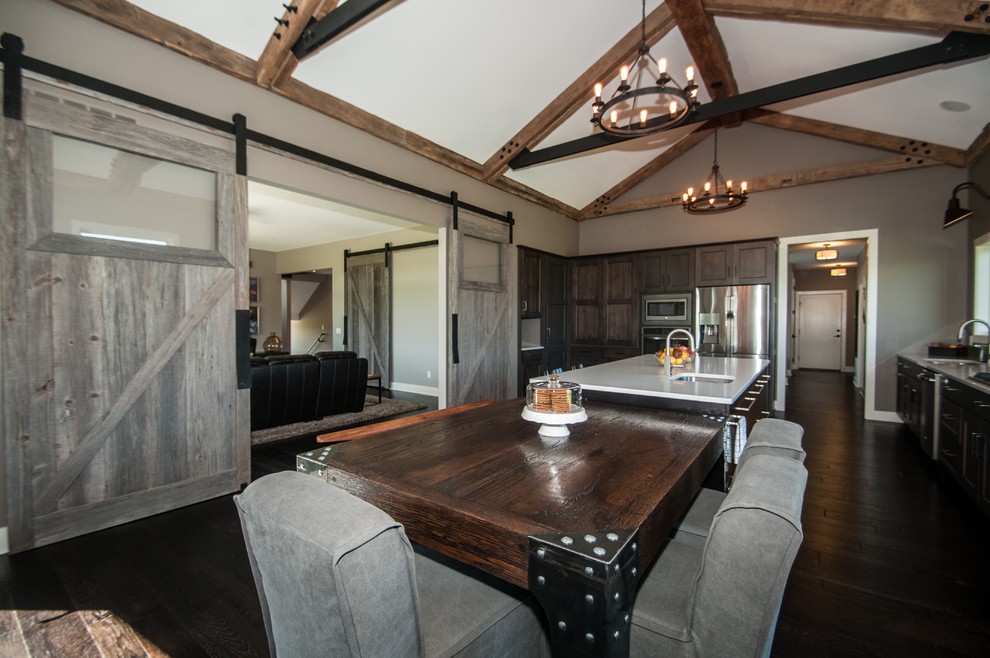 Example of a large mountain style dark wood floor and brown floor eat-in kitchen design with an undermount sink, flat-panel cabinets, medium tone wood cabinets, quartz countertops, green backsplash, glass sheet backsplash, stainless steel appliances and an island