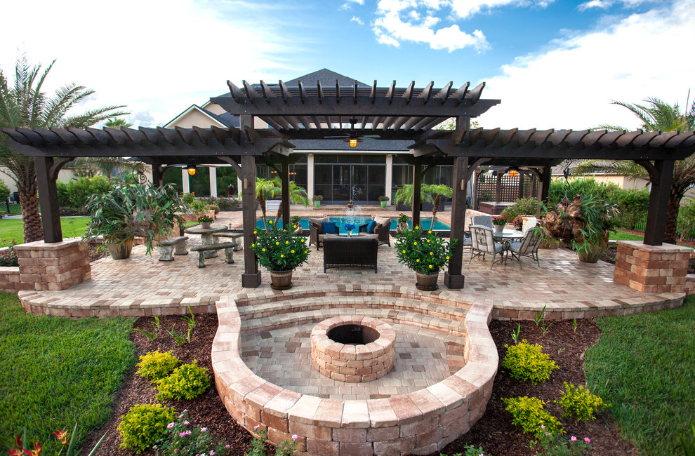 This is an example of an expansive traditional backyard patio in Jacksonville with a fire feature, natural stone pavers and a pergola.