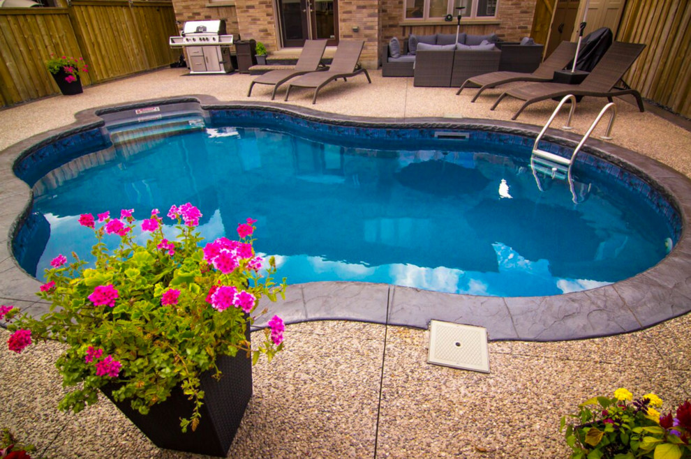 Design ideas for a small transitional backyard kidney-shaped pool in Toronto with stamped concrete.