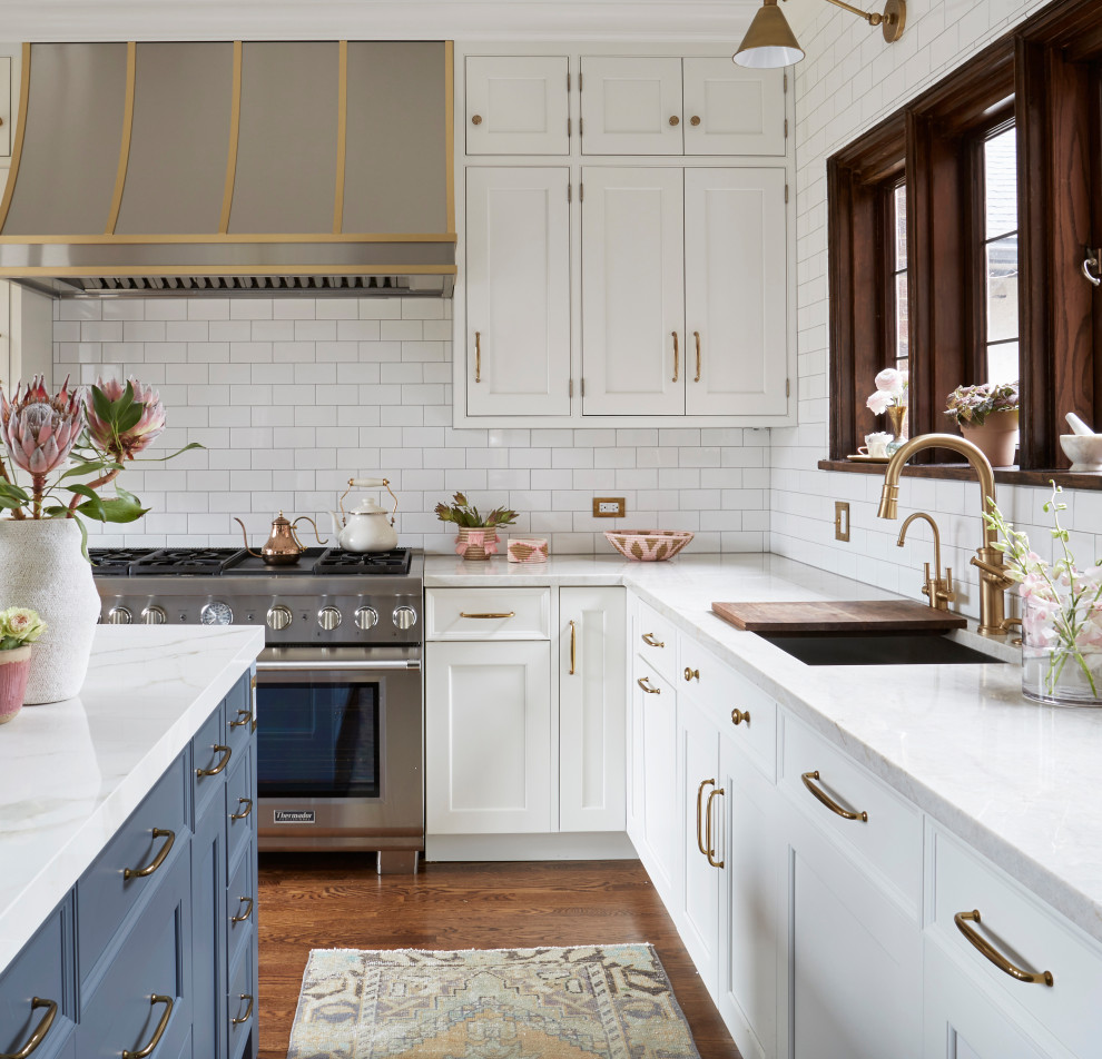 Example of a transitional l-shaped medium tone wood floor kitchen design in Chicago with blue cabinets, white backsplash, subway tile backsplash, stainless steel appliances, an island and white countertops