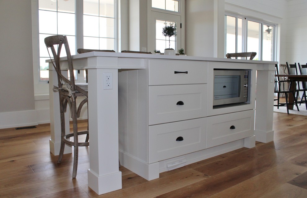 Inspiration for a large transitional l-shaped eat-in kitchen remodel in Toronto with an undermount sink, shaker cabinets, white cabinets, quartz countertops, white backsplash, stainless steel appliances and an island