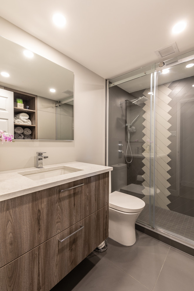 Contemporary 3/4 bathroom in Montreal with flat-panel cabinets, medium wood cabinets, an alcove shower, gray tile, white tile, white walls, an undermount sink, grey floor, a sliding shower screen and white benchtops.