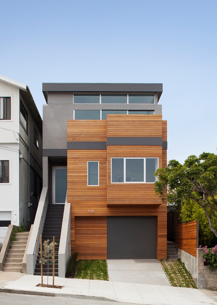 This is an example of a contemporary three-storey grey house exterior in San Francisco with wood siding and a flat roof.