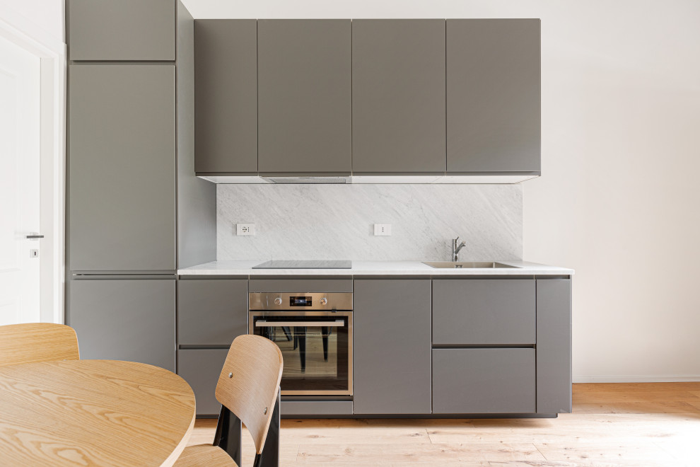 Small scandinavian single-wall eat-in kitchen in Milan with light hardwood floors, brown floor, wood, an undermount sink, flat-panel cabinets, grey cabinets, marble benchtops, white splashback, marble splashback, stainless steel appliances, no island and white benchtop.