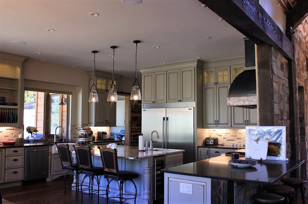 Huge mountain style l-shaped open concept kitchen photo with an undermount sink, quartz countertops, beige backsplash, stone tile backsplash, stainless steel appliances and an island