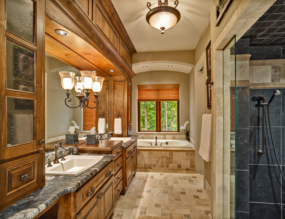 Photo of a large traditional master bathroom in Other with raised-panel cabinets, medium wood cabinets, a drop-in tub, an alcove shower, a two-piece toilet, beige tile, stone tile, beige walls, travertine floors, a drop-in sink and granite benchtops.