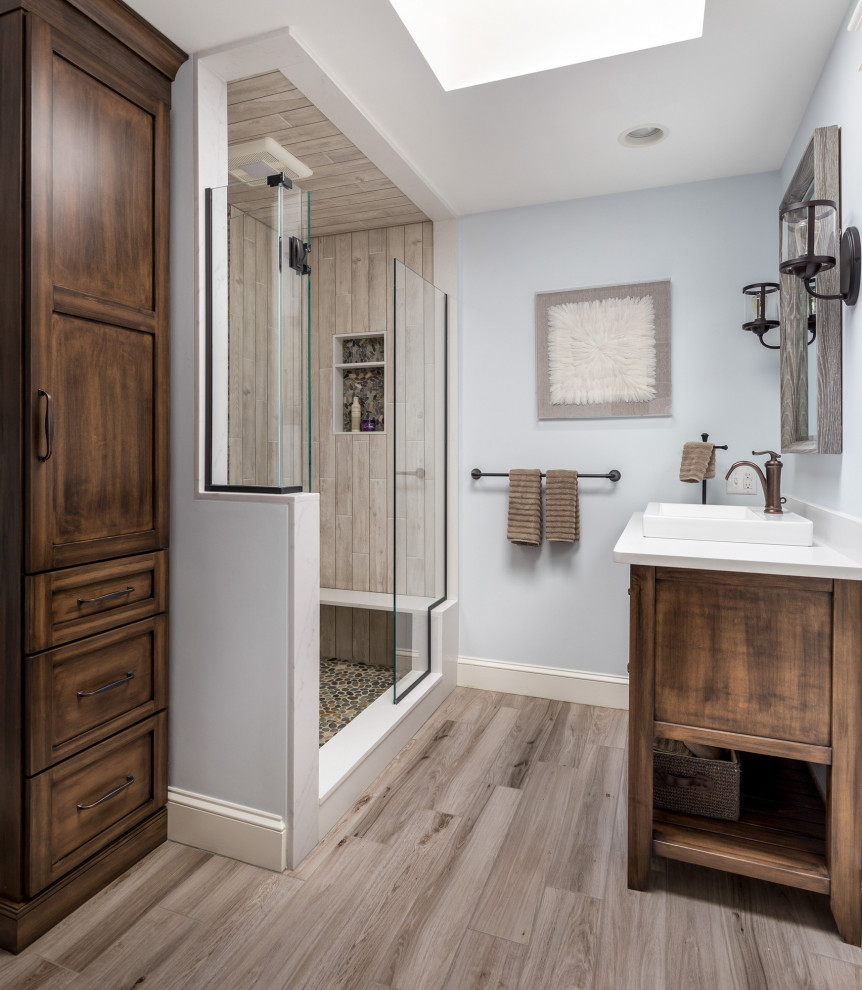 Design ideas for a mid-sized transitional master bathroom in Boston with flat-panel cabinets, a one-piece toilet, brown tile, porcelain tile, porcelain floors, a drop-in sink, engineered quartz benchtops, brown floor, a hinged shower door, white benchtops, medium wood cabinets, an alcove shower and blue walls.