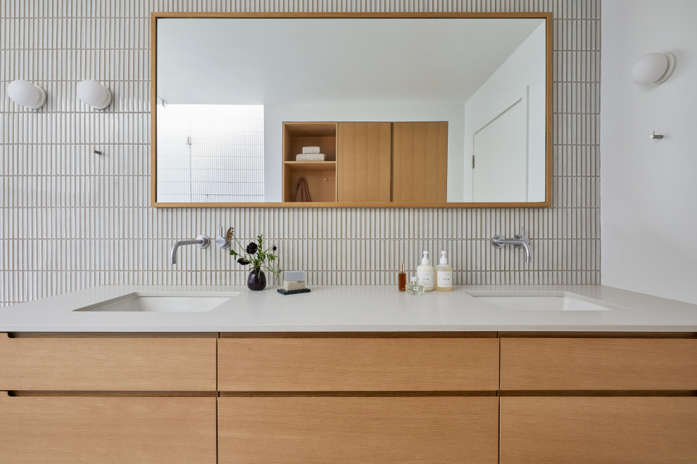 Example of a large minimalist master white tile and ceramic tile porcelain tile, beige floor and double-sink bathroom design in San Francisco with flat-panel cabinets, brown cabinets, a one-piece toilet, white walls, an undermount sink, quartz countertops, a hinged shower door and gray countertops