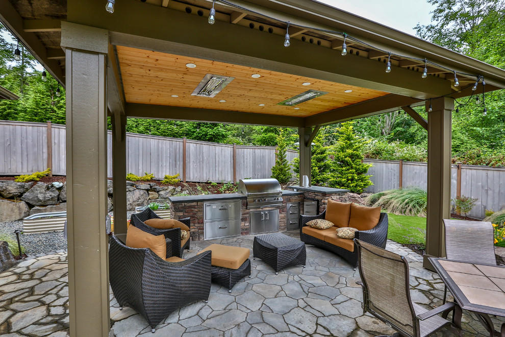 Large modern backyard patio in Seattle with an outdoor kitchen, natural stone pavers and a gazebo/cabana.