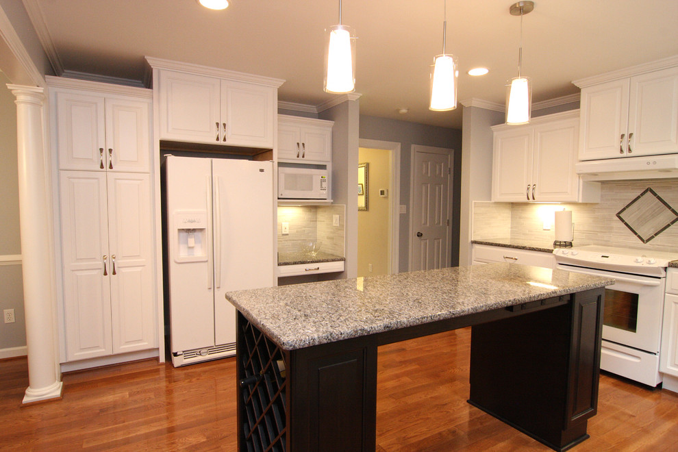Example of a mid-sized transitional u-shaped medium tone wood floor eat-in kitchen design with an undermount sink, raised-panel cabinets, white cabinets, granite countertops, gray backsplash, porcelain backsplash, white appliances and an island