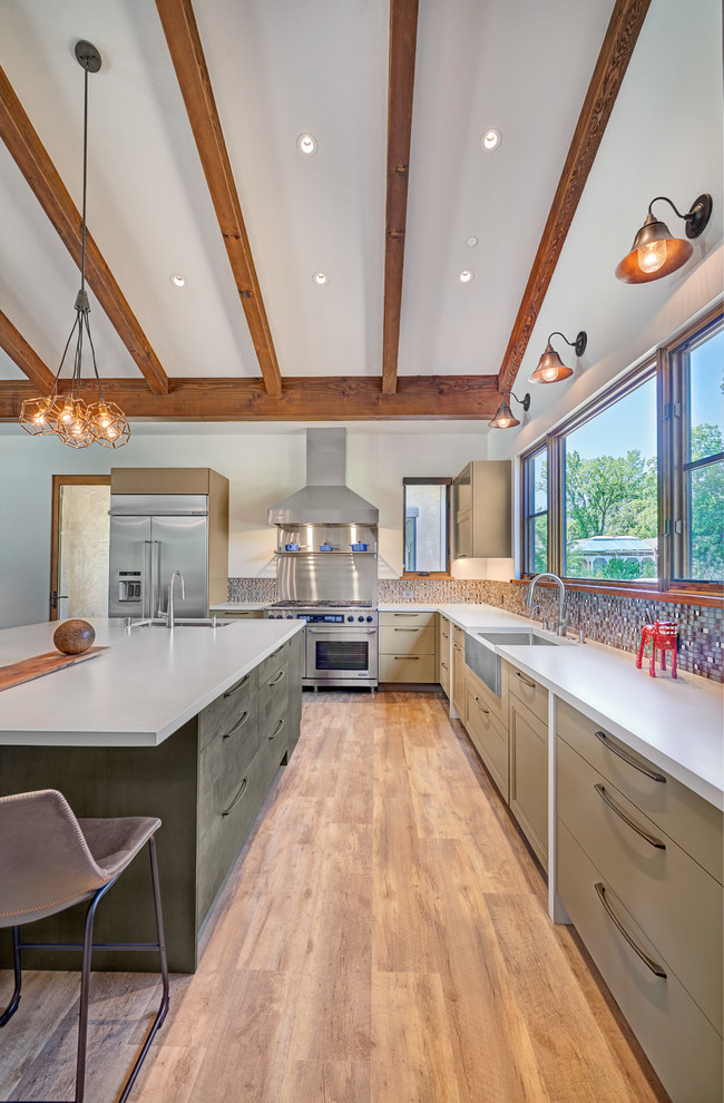 Large country u-shaped open plan kitchen in Sacramento with a farmhouse sink, recessed-panel cabinets, green cabinets, quartz benchtops, metallic splashback, mosaic tile splashback, stainless steel appliances, vinyl floors, with island, brown floor and white benchtop.