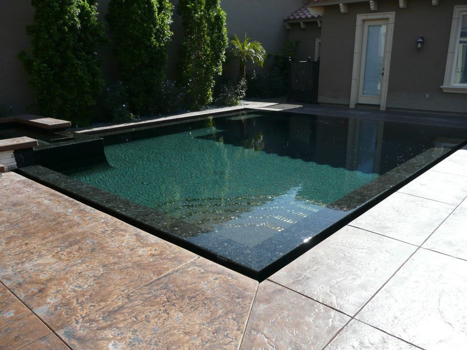 Inspiration for a mid-sized backyard rectangular infinity pool in Los Angeles with stamped concrete and a hot tub.